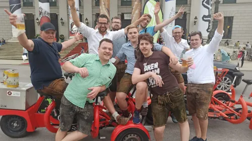 Group of partying men pose on a bicycle.