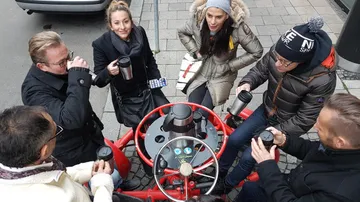 Gruppe von Menschen trinkt Kaffee an einem roten Tisch.