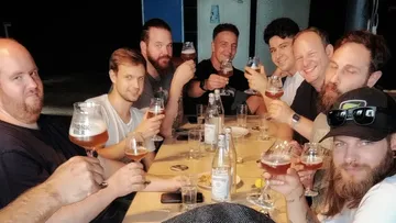 gruppe leute hebt biergläser in geselliger runde an einem tisch.
