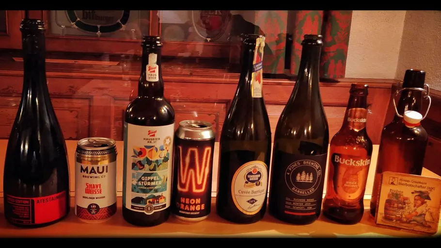 Various craft beer bottles and cans on a table.