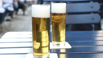 Zwei Biergläser stehen auf einem Tisch im Freien.