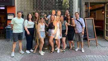Group of people pose smiling in front of a restaurant.