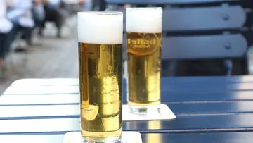 Zwei Biergläser stehen auf einem Tisch im Freien.