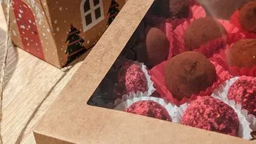 Geschenkbox mit Schokoladentrüffeln auf einem Holztisch.