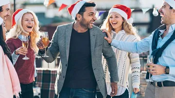 Gruppe von Menschen mit Weihnachtsmützen, die draußen lachen.