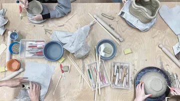 Pottery tools and clay are used by several people.