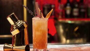 Cocktailglas mit Getränk, dekoriert, vor einer Bar.