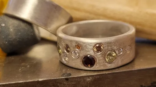 A ring with precious stones lies on a metal surface.