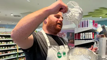 A man whips cream in a shop with products.