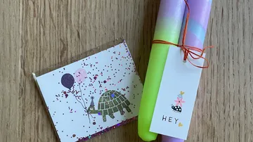 Bunte Kerzen liegen neben einer glitzernden Grußkarte.
