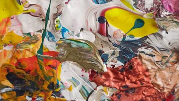 Bunte Farbkleckse vermischen sich auf einer strukturierten Oberfläche.