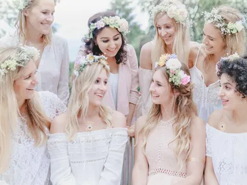 Eine Gruppe von Frauen lächelt, umgeben von Blumen.