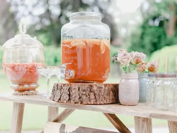 Glass container with drink on a wooden outdoor table.