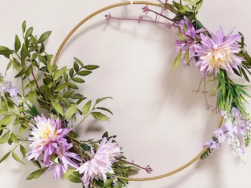 Flower wreath hangs decoratively on white wall.