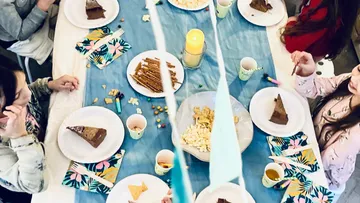 Kinder sitzen an einem dekorierten Tisch und essen Kuchen