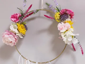 Blumenkranz hängt dekorativ an einer Wand.
