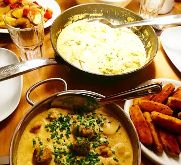 Stew dish with balls and side dishes on the table.
