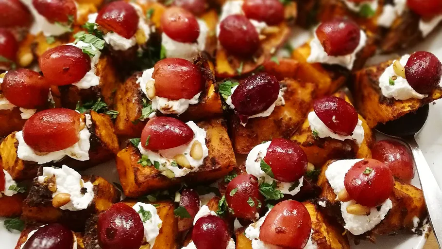 Roasted sweet potato pieces with grapes and cream cheese topping.