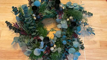 Decorative wreath with foliage on wooden table.