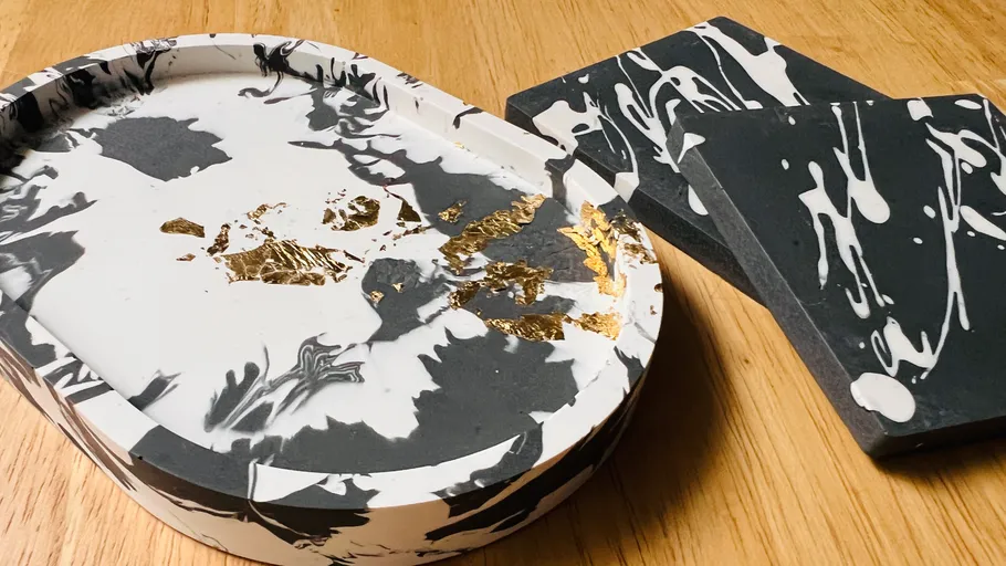 Tablett und Untersetzer mit Marmormuster mit goldenen Akzenten.