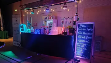 Bar mit Neonbeleuchtung und Getränkekarte an der Tafel.