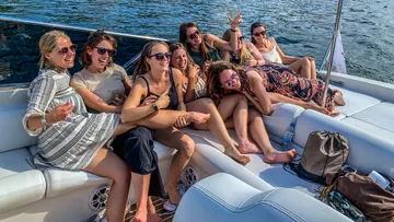 Gruppe von Frauen, die auf einem Bootsdeck lachen.