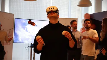 Person mit VR-Headset jongliert in einer Partyumgebung.
