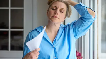 Frau mit einem Papier in der Hand, entspannt zu Hause.