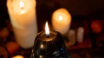 Black candle burns surrounded by more candles