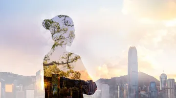 Silhouette of a woman with cityscape and trees in the background.