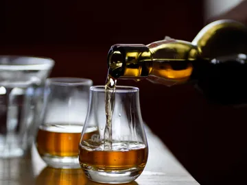 Ein Glas wird mit goldfarbener Flüssigkeit gefüllt.