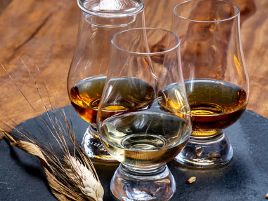 Three glasses of various drinks on a black plate.