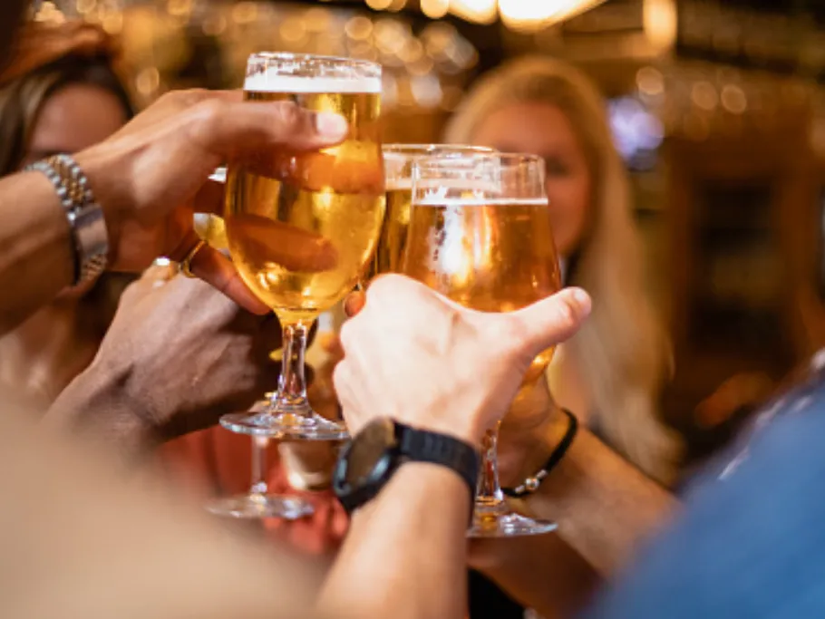 Glasses of beer are toasted in a convivial environment.