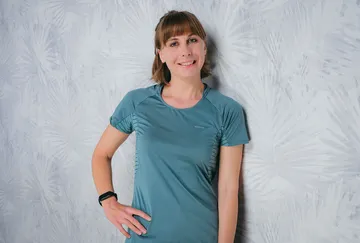 Woman standing next to a bright, patterned wall, smiling.