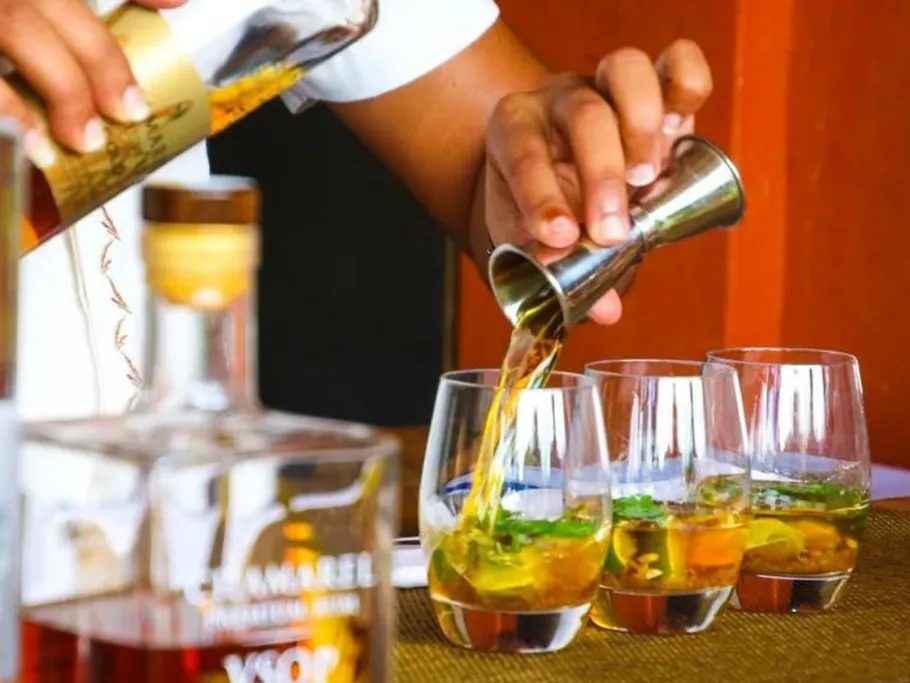 A bartender pours drinks into several glasses.