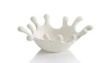 Weißer Schalenobjekt spritzt, minimalistische Umgebung präsentiert.