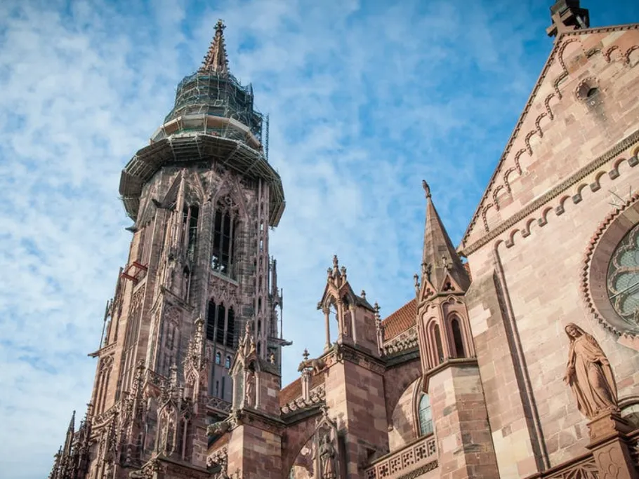 Gotische Kirche mit einem hohen, gerüsteten Turm im Himmel.
