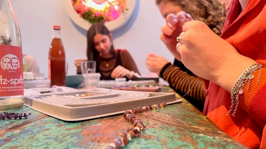 People crafting jewelry at a table workshop.