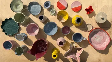 Colourful ceramics are scattered on a light wooden background.