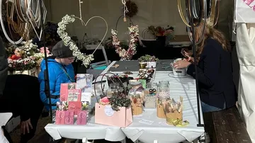 Market table with craft materials, two people create handicrafts.