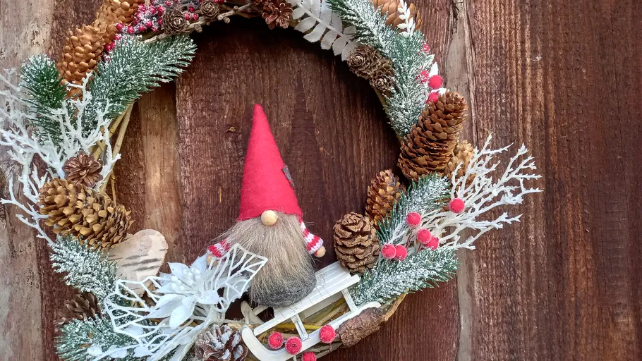 A wreath with pine cones and a red gnome.