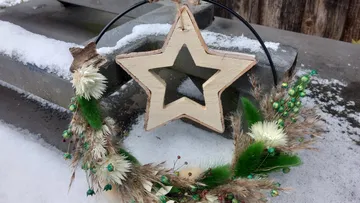 Wooden star wreath on snowy ledge.