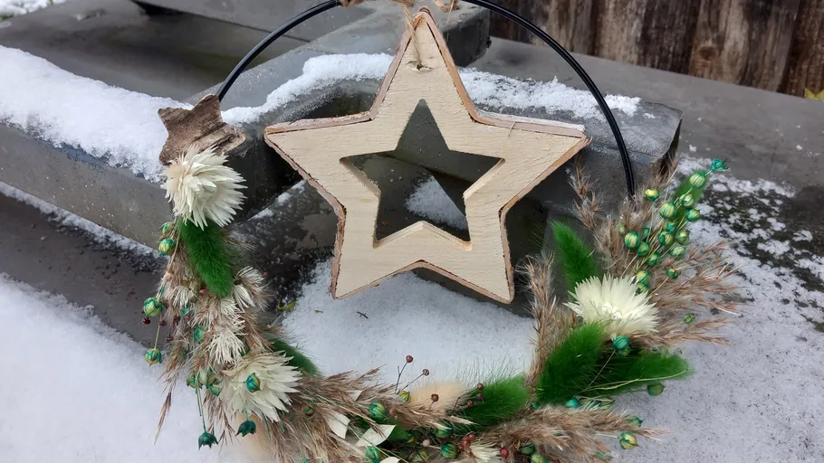 Wooden star wreath on snowy ledge.