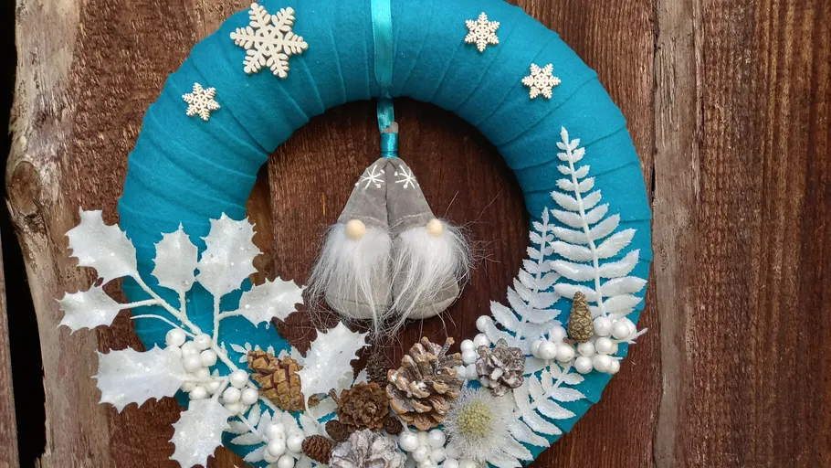 Door wreath with festive decoration on a wooden wall.
