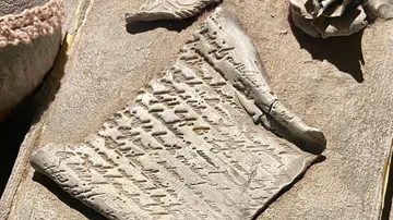 Clay tablet with engraved characters on a table.