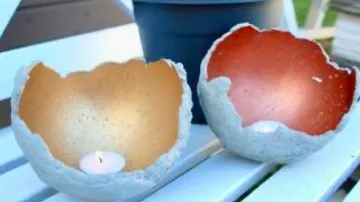 Two bowls with candlelight stand on a white surface.