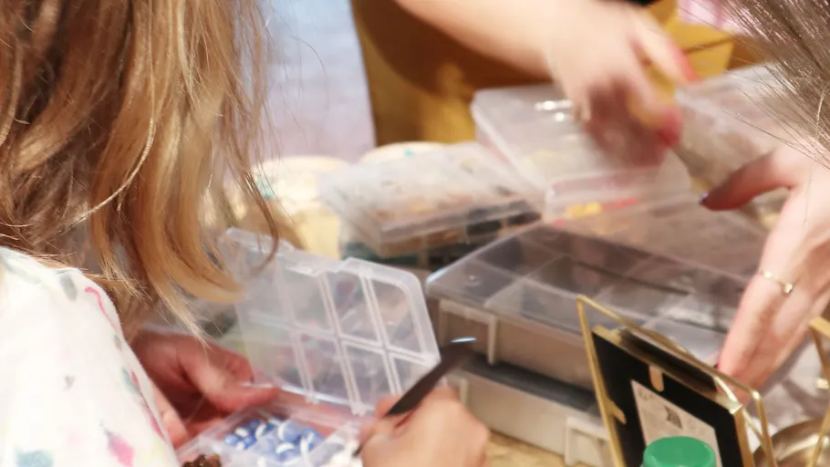 Hands sort craft materials on a table.