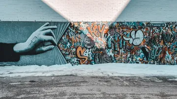 Hand zieht einen Vorhang zurück, um Graffiti zu zeigen.
