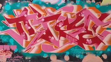 Bunte Graffiti-Wandmalerei mit stilisierten Buchstaben.