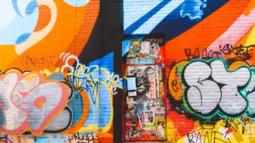 Bunte Wand mit Graffiti und einer Tür in der Mitte.